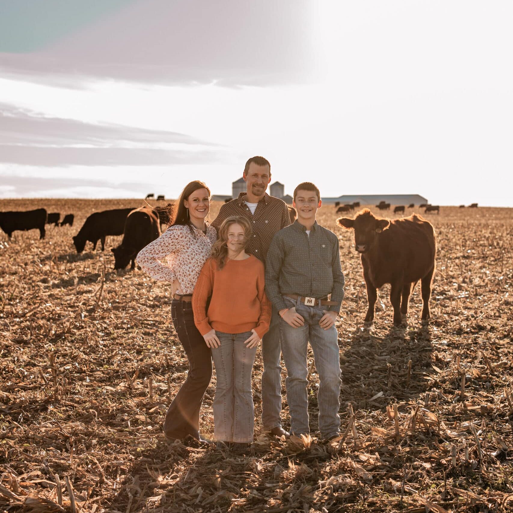 Mandy Anderson with Family of four in the field and cows in the background